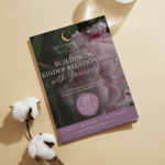 A thin printable booklet titled Building a Kinder Relationship with Yourself lying on a warm beige background next to a glass of water and cotton flowers.
